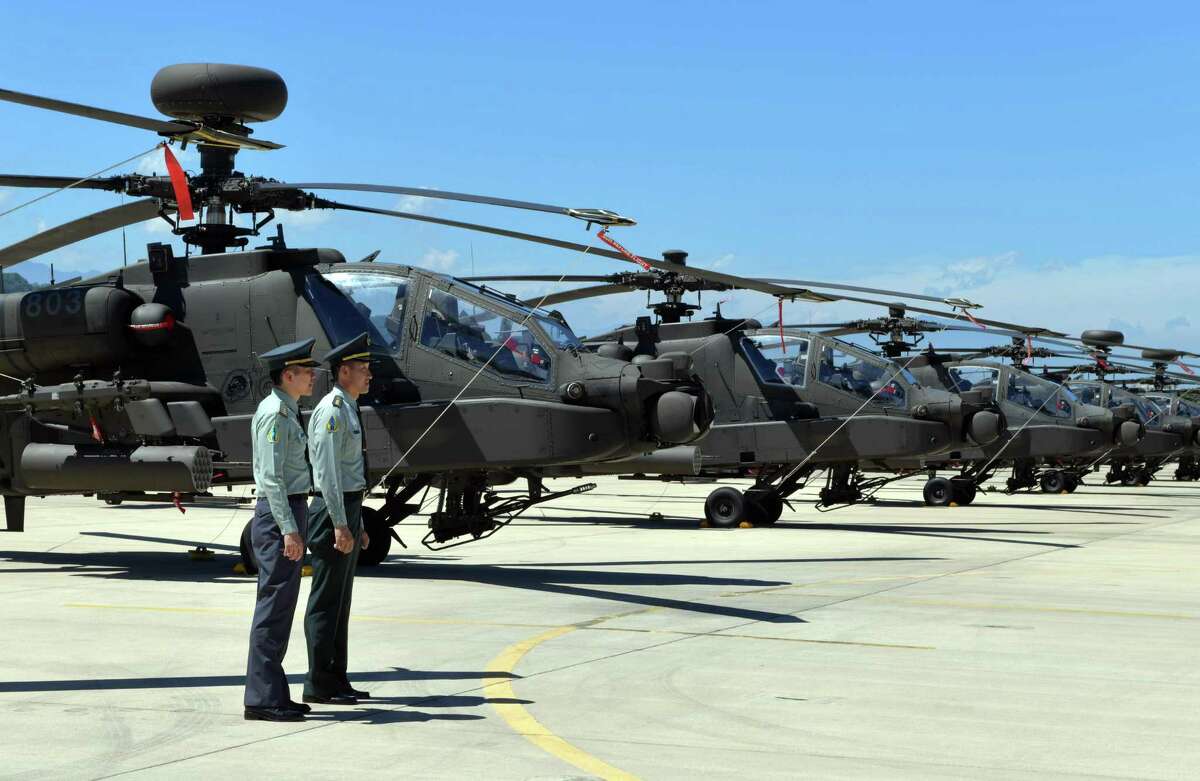 Two Taiwan servicemen stand in front of US-made Apache AH-64E attack helicopters during a commissioning ceremony at an military base in Taoyuan on July 17, 2018. The Taiwanese army was the first force outside the United States to introduce the AH-64E variant back in 2013.