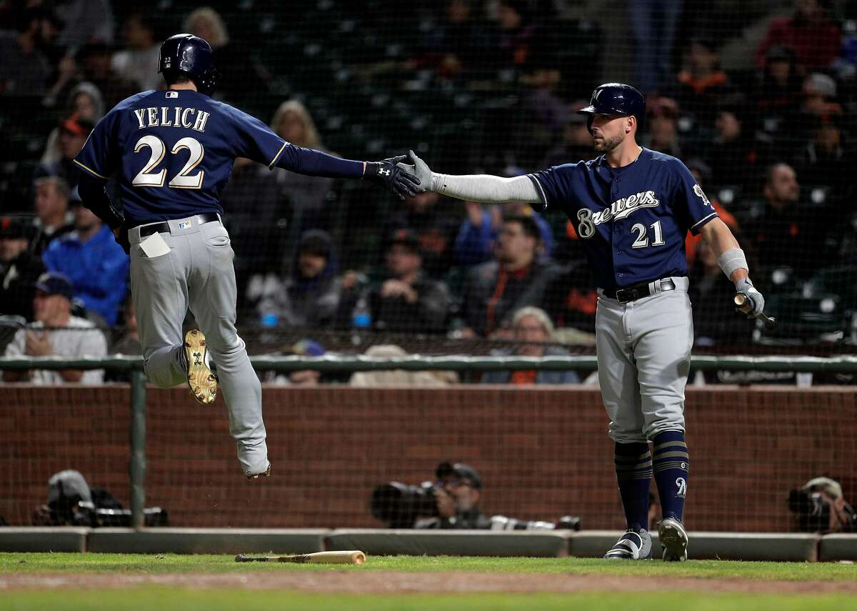 Christian Yelich (22) hops up as he high fives Travis Shaw (21) after scoring in the eighth inning as the San Francisco Giants played the Milwaukee Brewers at AT&T Park in San Francisco, Calif., on Thursday, July 26, 2018.