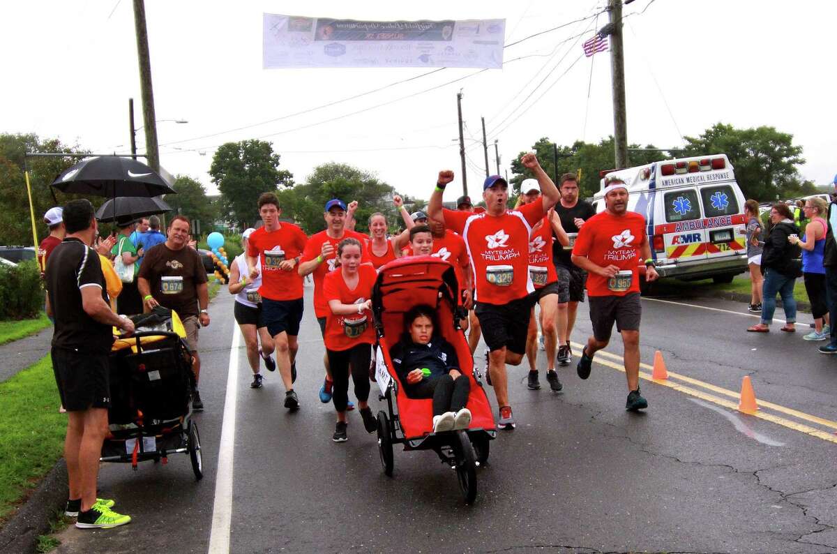 Members of myTeam Triumph, with Sami Leskin, of Westport, in a team wheelchair, approach the finish line after running in the Fairfield Police Department Sunset 5K. The group will participate in the SoNo Half Marathon and 5K Sunday in Norwalk.