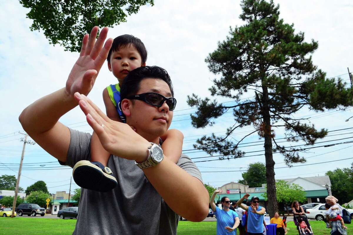 Daniel Chung, 3, sits on his dad Patrick's shoulder as he does Tai chi during the Family Fitness Day on Paradise Green in Stratford, Conn., on Saturday, July 28, 2018. The event, held by Get Healthy CT, coincides with National Dance Day and encourages area residents of all ages to be physically active and eat healthy foods.