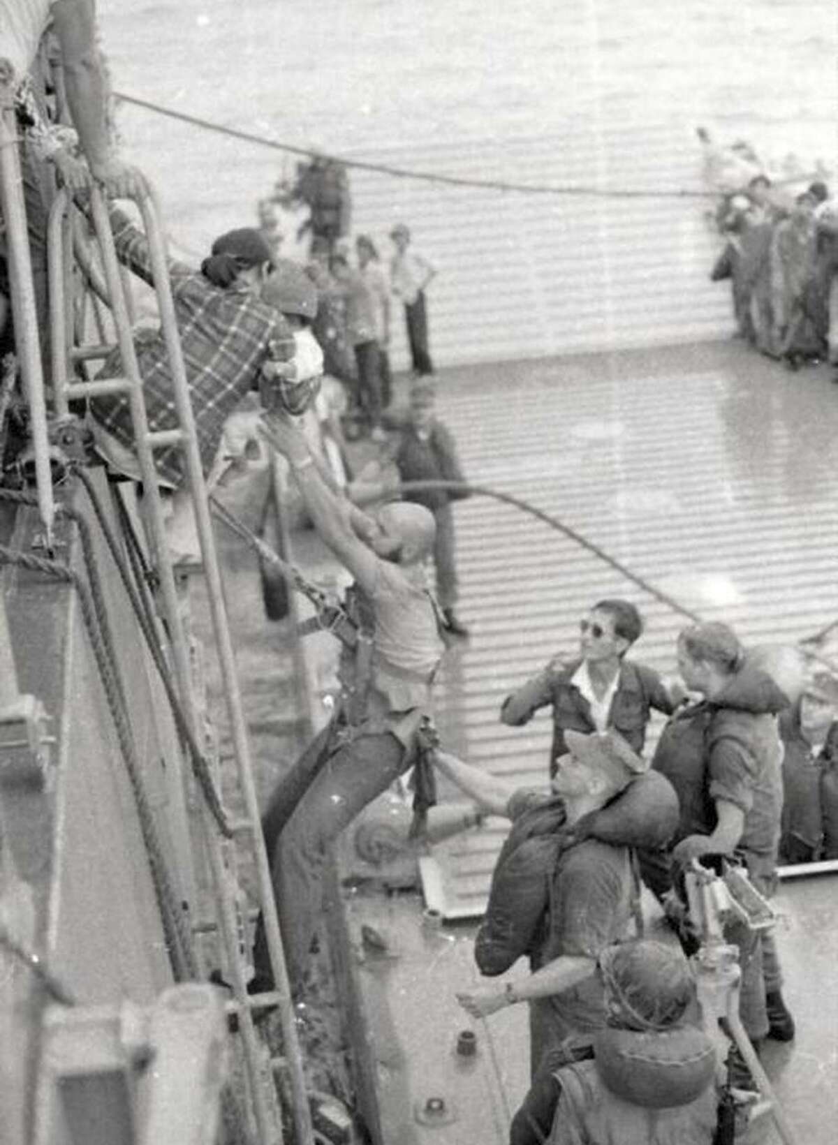 Hong Thi Le and infant An Le are helped down a ladder by sailors aboard the Blue Ridge after being flown by helicopter from Saigon in 1975. Hung Le, An’s father and the pilot of the chopper, is at the bottom of the ladder, wearing sunglasses.