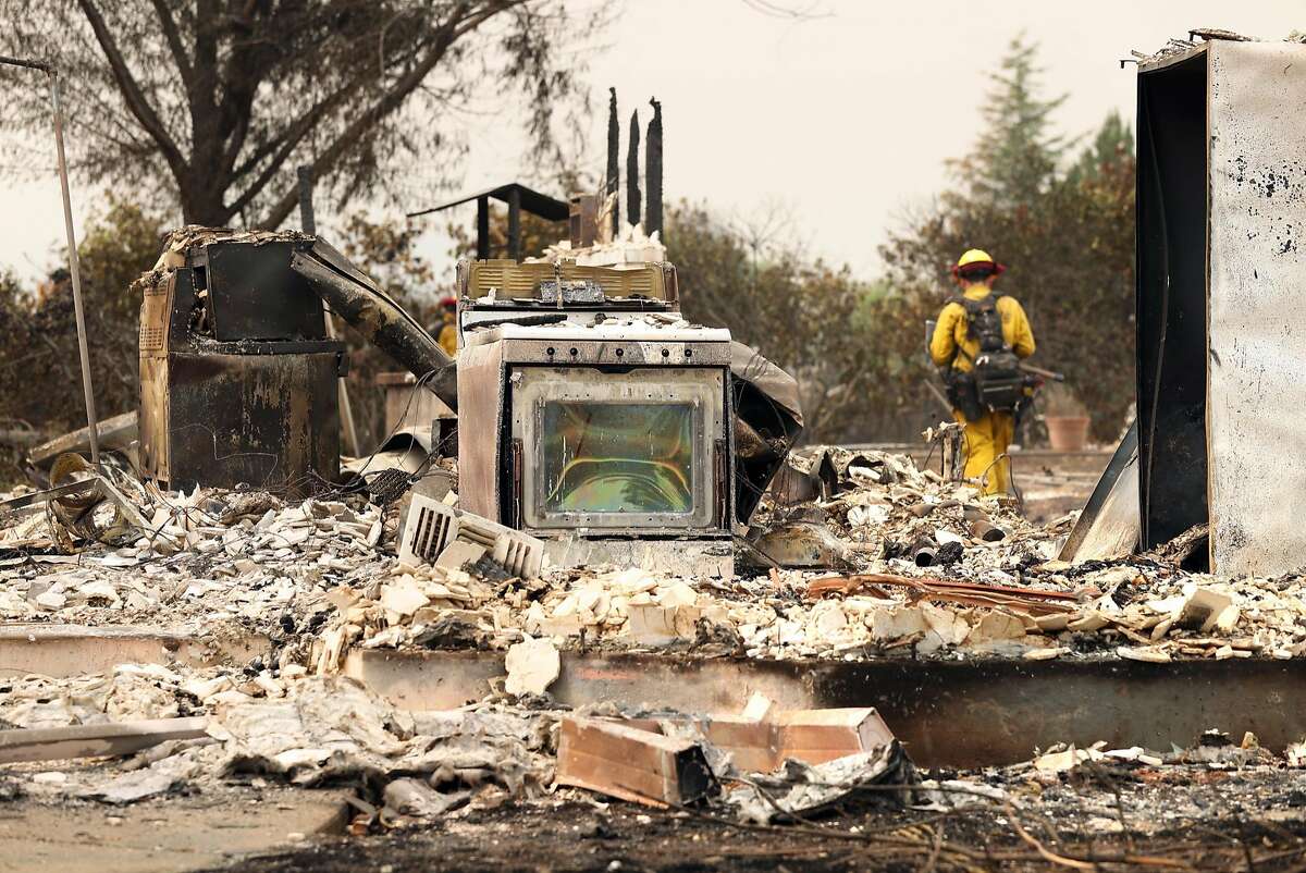 A Cal Fire crew member from San Diego puts out hot spots amongst destroyed houses on Menlo Way in the aftermath of the Carr Fire in Redding, Calif. on Sunday, July 29, 2018.
