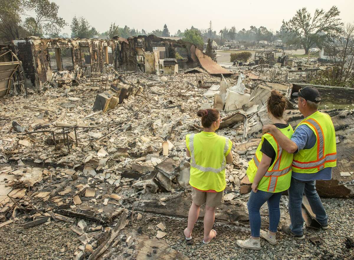 Anna Noland (left), 16-year-old Kailyn Nash and James Nash at their burned home in the Lake Keswick Estates neigh bor hood of Redding. Thousands of firefighters scrambled to push the fire away from the shaken Shasta County town.
