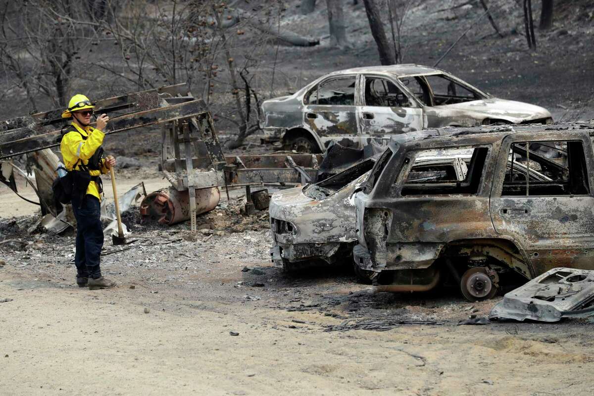 San Bernardino County Fire Department firefighter James Lippen takes photos of the damage caused by a wildfire, Sunday, July 29, 2018, in Keswick, Calif. (AP Photo/Marcio Jose Sanchez)