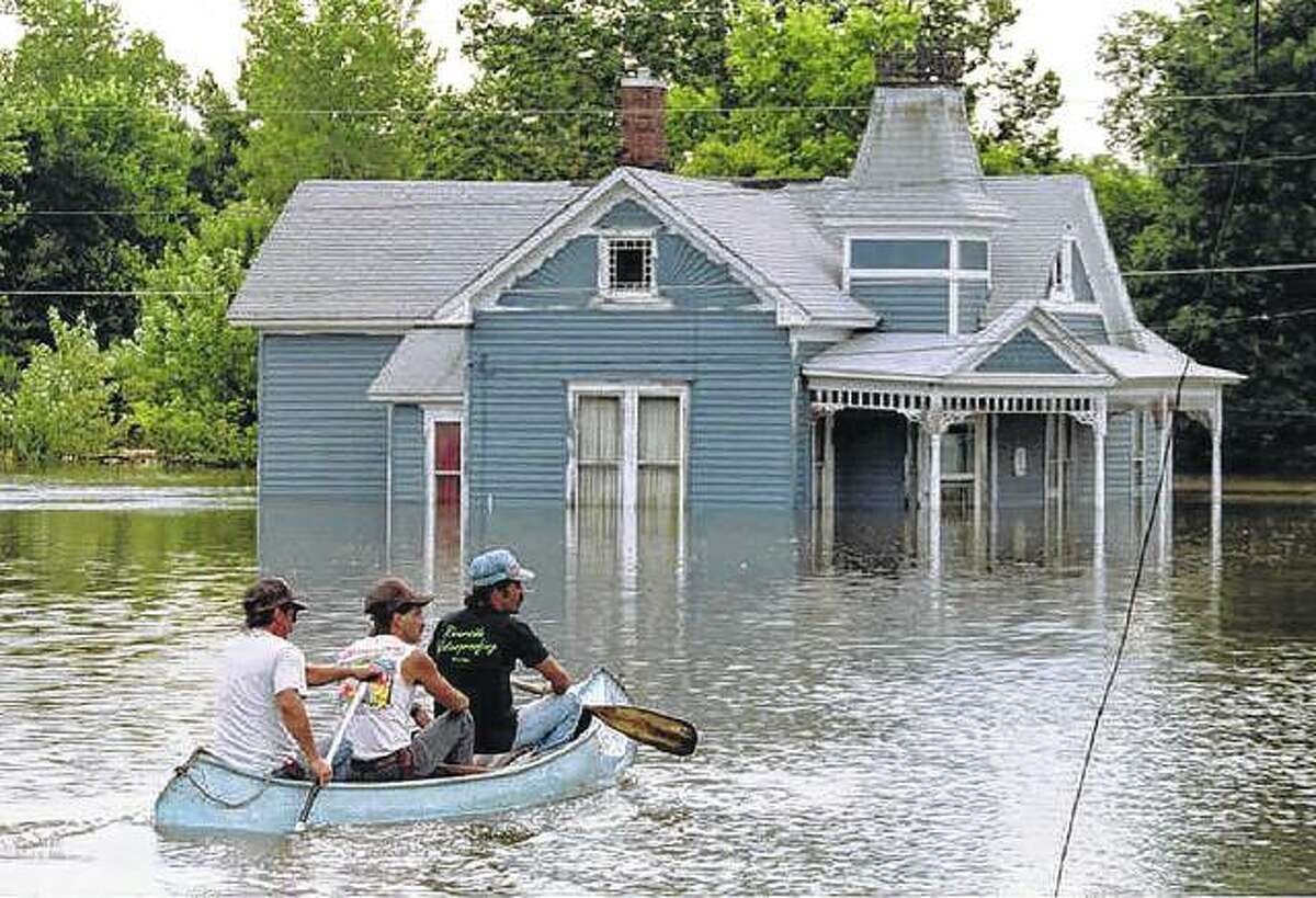 Brothers John, Jerry and Ed Tharp canoe through the flooded streets of their town in July 1993 after the rising Mississippi River breached the town levee.