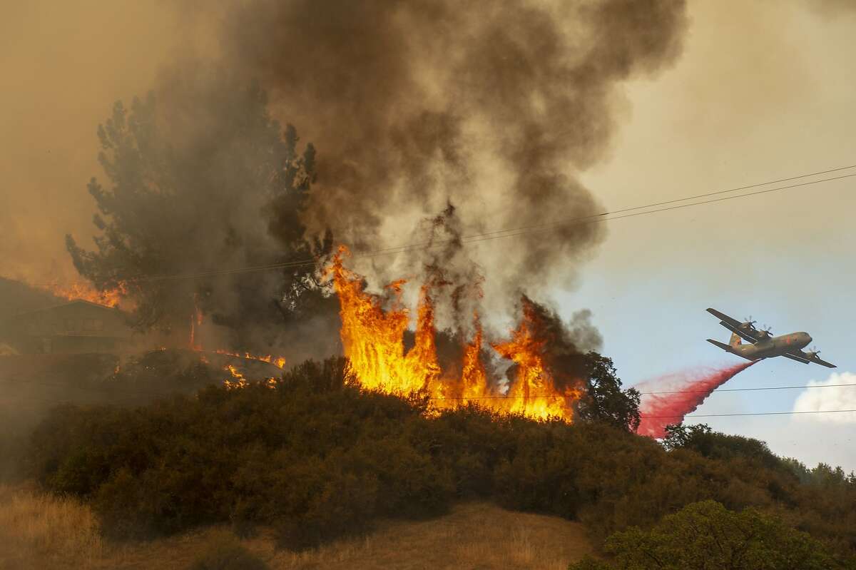 Fire retardant is dropped near a home as a wildfire burns off of Keck Road, just west of Lakeport, Calif., Monday, July 30, 2018. A pair of wildfires that prompted evacuation orders for nearly 20,000 people barreled Monday toward small lake towns in Northern California, and authorities faced questions about how quickly they warned residents about the largest and deadliest blaze burning in the state. (Jose Luis Villegas/The Sacramento Bee via AP)