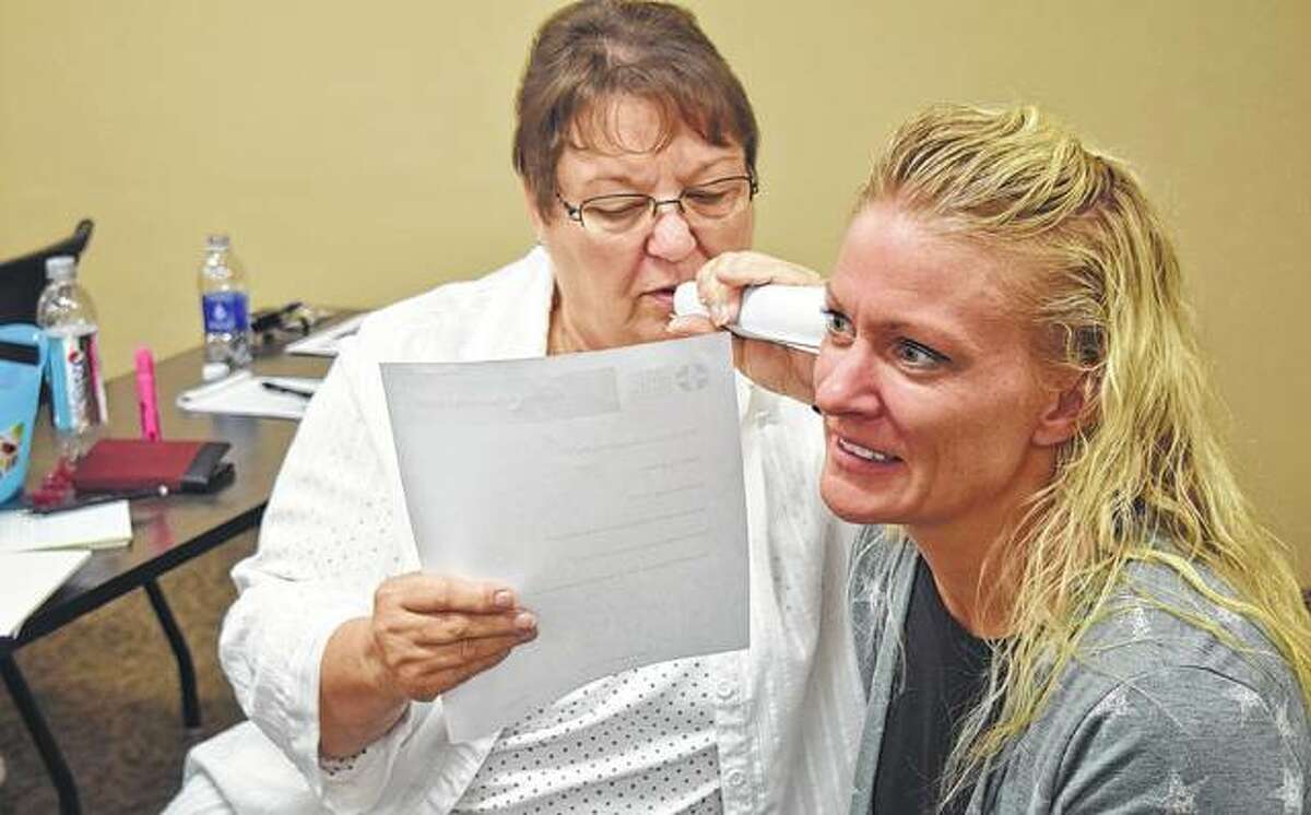 Carol Christensen (right) of Jacksonville tries to have a conversation while Sheila Chapman of Jacksonville whispers in her ear during an exercise Monday that was part of Youth Mental Health First Aid Training. The exercise is supposed to imitate an auditory hallucination.