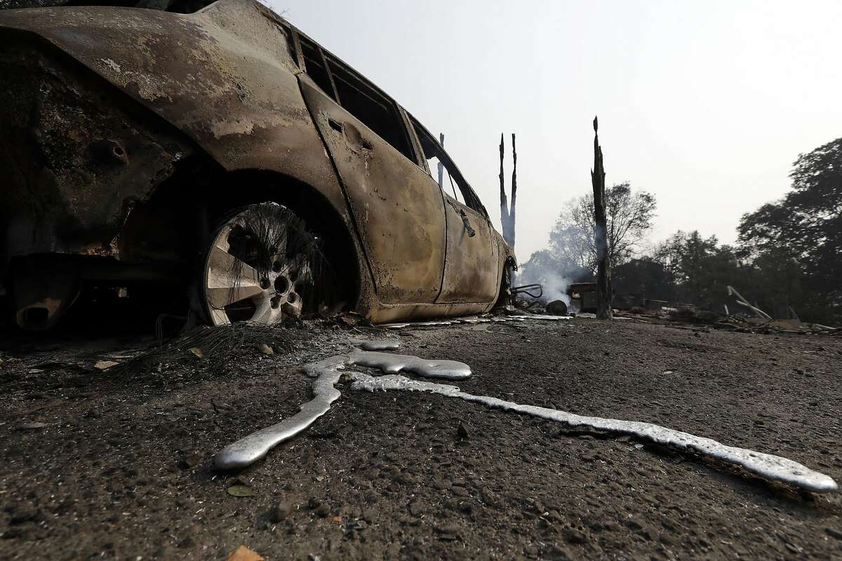 Melted metal is seen under a wildfire- damaged car Tuesday, July 31, 2018, in Lakeport, Calif. Battalion Chief John Messina said Tuesday fire crews slowed the spread of one of the blazes into towns near Clear Lake, including Lakeport, a city of 5,000. He says the fire instead spread into the Mendocino National Forest. (AP Photo/Marcio Jose Sanchez)