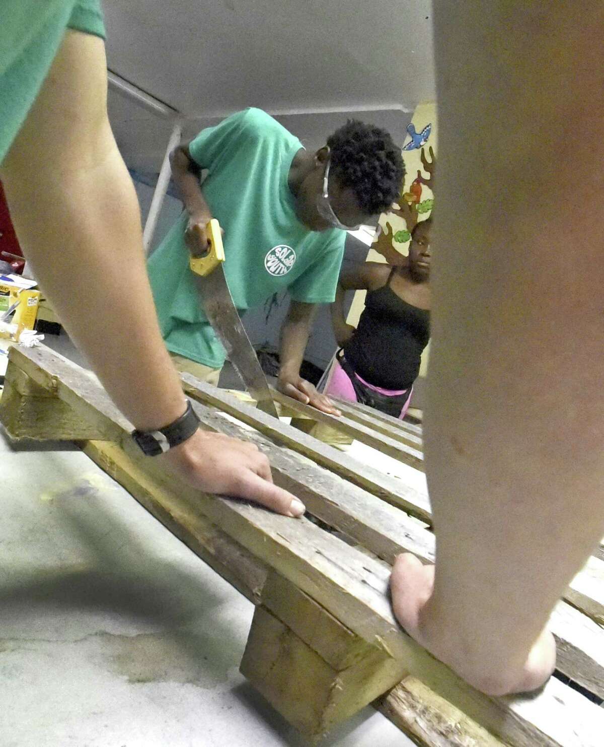 Zarquis Sanders of New Haven, 17, helps prepare a recycled wood pallet that will be turned into a bench for an outside community space as part of the Solar Youth Green Jobs program in New Haven.