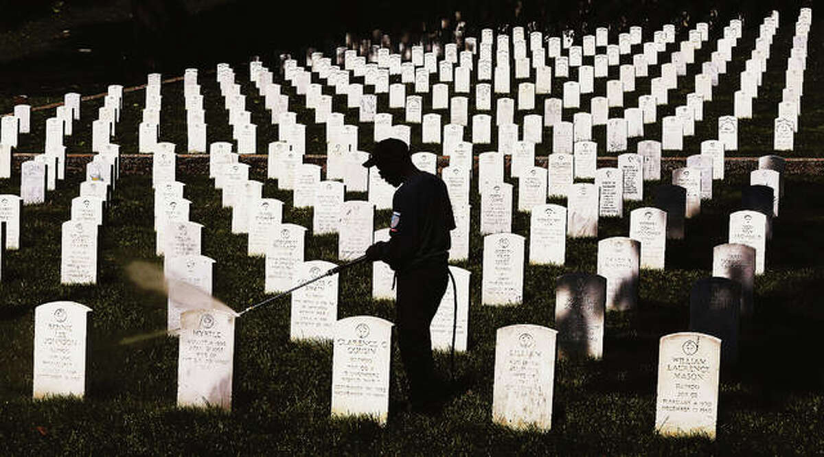 In this Telegraph file photo, an employee of BOCO Contracting & Construction, LLC, a Brighton veteran owned business, is silhouetted against the white headstones in the Alton National Cemetery on Pearl Street as he was power washing the headstones.
