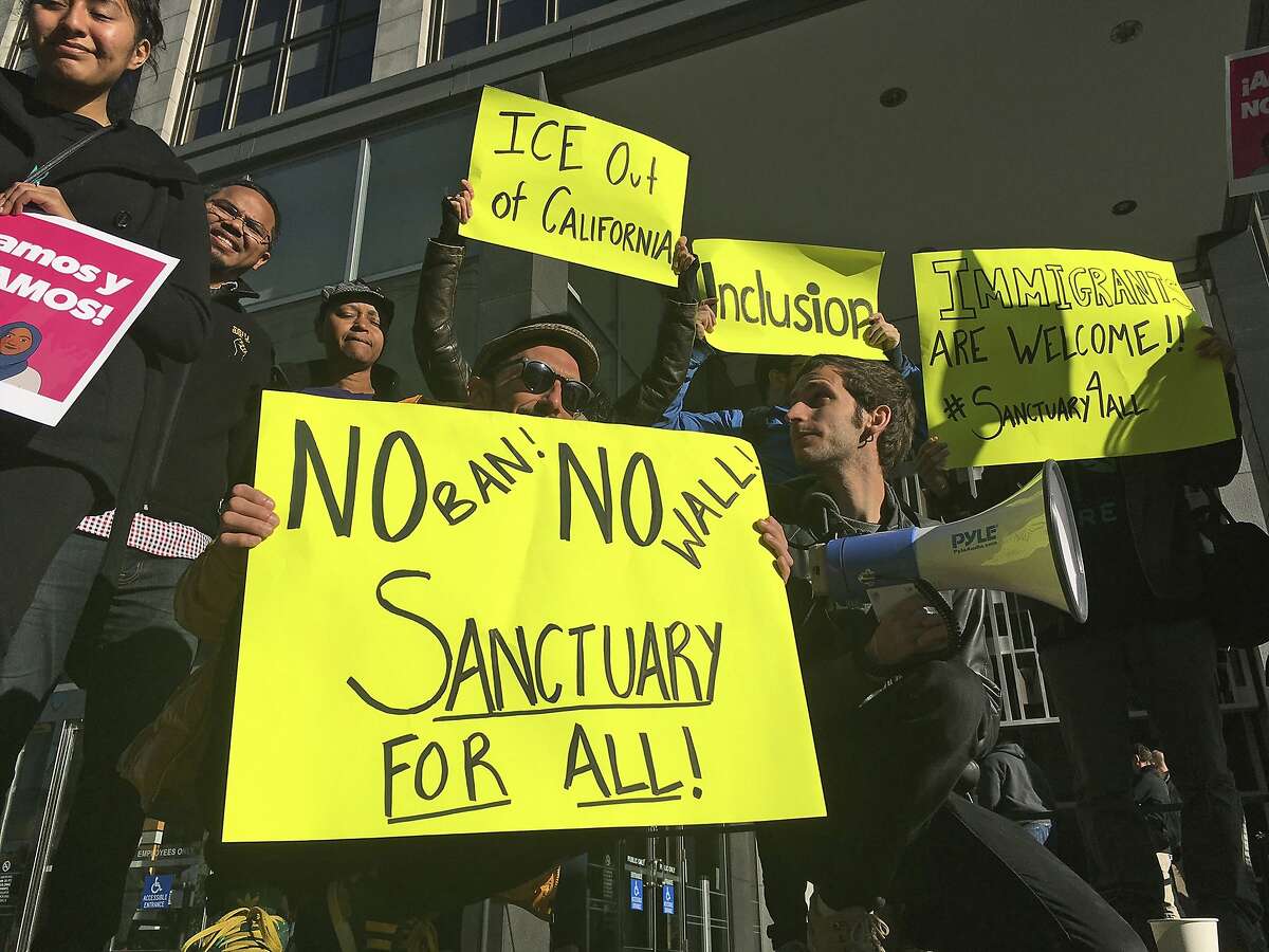 FILE - In this April 14, 2017, file photo, protesters hold up signs outside a courthouse in San Francisco. President Donald Trump's executive order threatening to withhold funding from "sanctuary cities" that limit cooperation with immigration authorities is unconstitutional, but a judge went too far when he blocked its enforcement nationwide, a U.S. appeals court ruled Wednesday, Aug. 1. (AP Photo/Haven Daley, File)