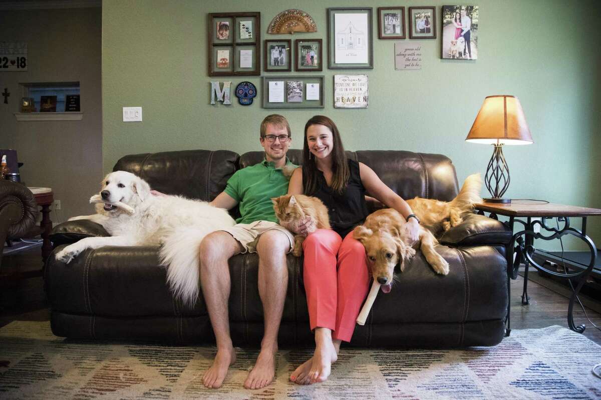 Laura Palmer and her fiancé Alex Mackay sit in their living room with their pets Moose, Cora and Puff in Houston. The medical residents purchased their first home last year, before they made the leap to get engaged. ( Marie D. De Jesús / Houston Chronicle )