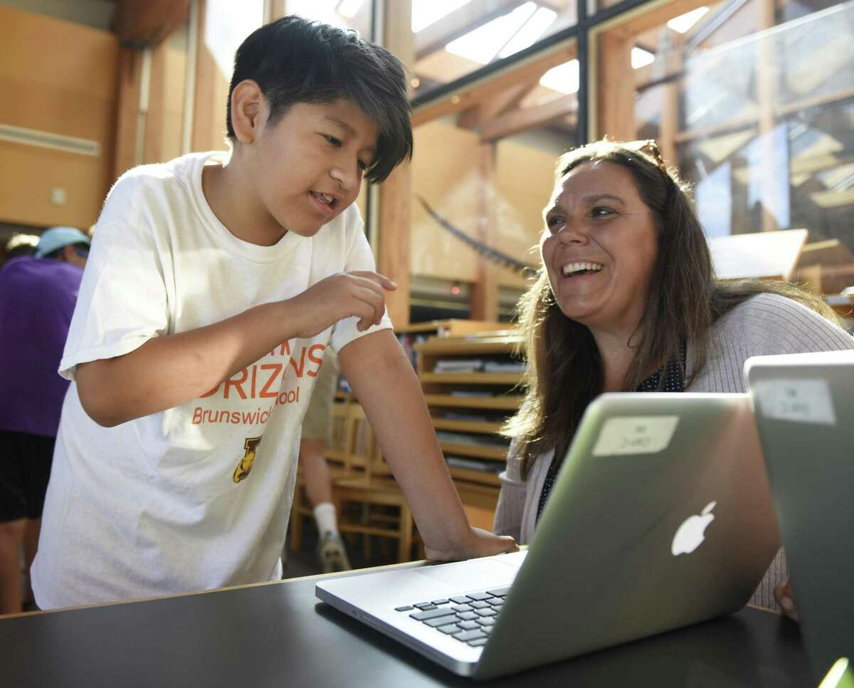 Rising sixth grader Richard Pesantez presents his project on Tod's Point to Horizons Academic Director Sarah Perez at the Brunswick Horizons photojournalism project showcase at Brunswick Lower School on the King Street campus in Greenwich, Conn. Thursday, Aug. 2, 2018. Rising sixth graders spent time observing and photographing local businesses and town establishments to learn communication and photography skills while gaining a sense of community. First graders and special guests were invited to see students' projects in a showcase Thursday morning.