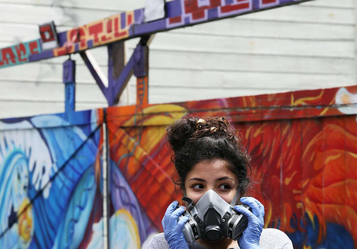 Leilani Deleon, 15, puts on a respirator mask before painting a mural during the Graffiti Camp for Girls in Clarion Alley in San Francisco, Cali. on Friday, July 27, 2018. The camp is led by Nina Wright, 32, founder and director of Graffiti Camp for Girls. Wright, a graduate from the Academy of Art University, runs the program with Deirdre O'Shea. Their aim is to empower young female artists.