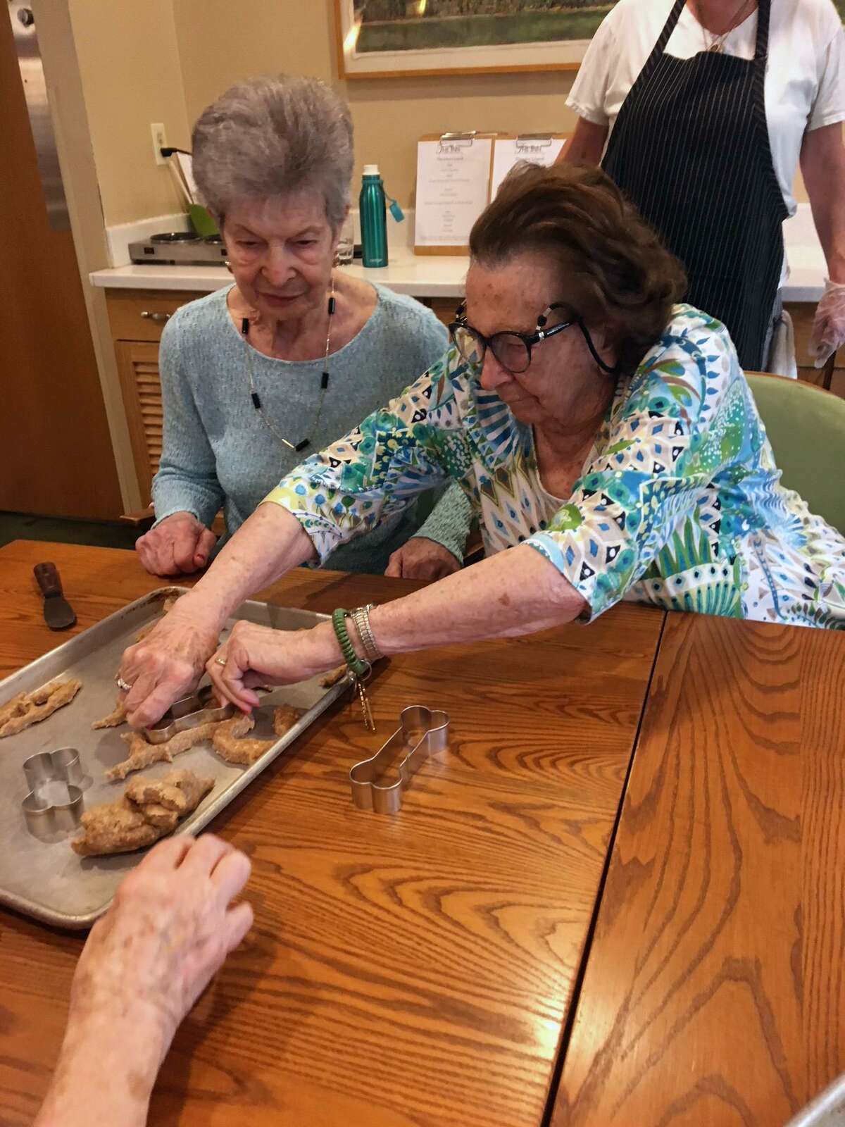 Using healthy ingredients, residents at The Inn at 73 Oenoke Ridge, in New Canaan, baked homemade dog biscuits, which they donated to PAWS of Norwalk. Rresidents Jennie and Ellie use bone-shaped cookie cutters to shape the biscuits, while Catherine flattens out the dough.