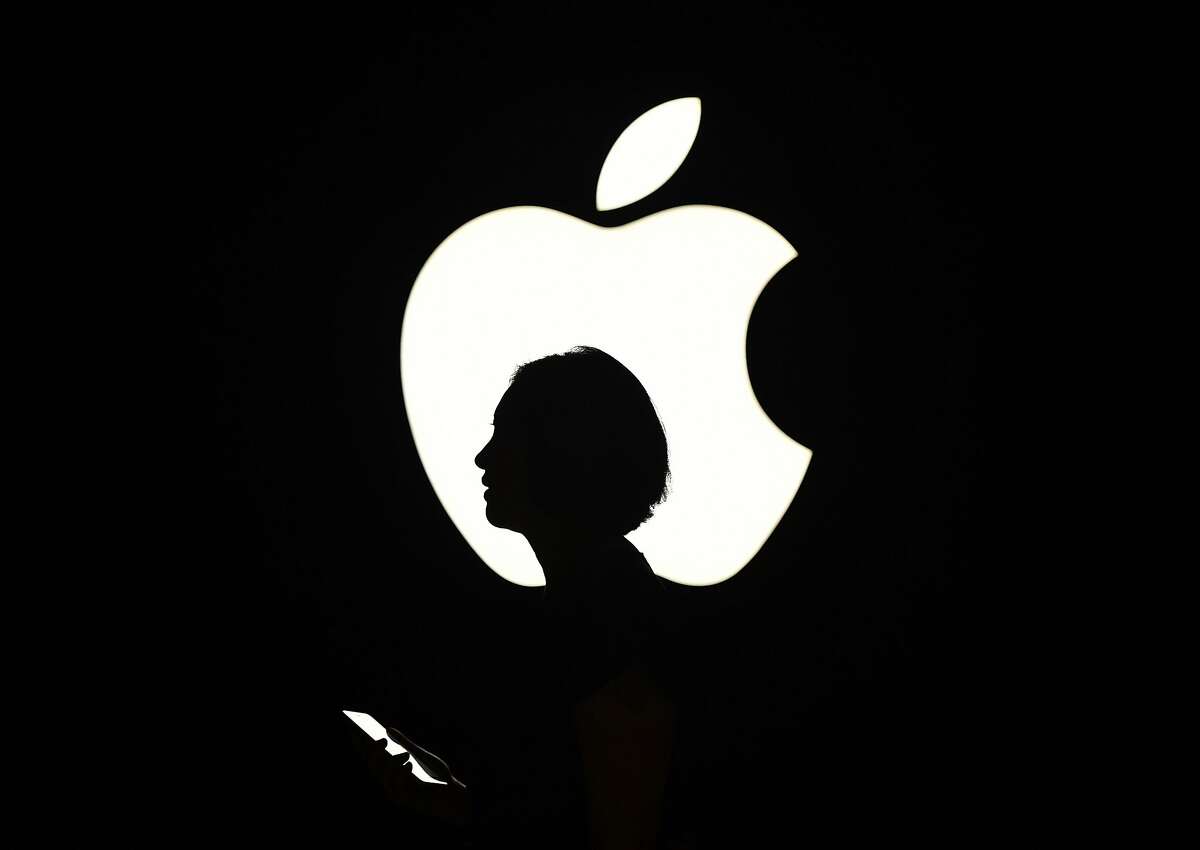 (FILES) In this file photo taken on September 9, 2015 a reporter walks by an Apple logo during a media event in San Francisco, California. Apple will release quarterly earnings figures July 31, 2018 as it flirts with a history-making, trillion-dollar market value based on its share price.To hit the trillion-dollar mark, Apple shares would have to climb about seven percent from the $189.91 price logged at the close of official trading Monday on the Nasdaq.The market is eager for news about demand for iPhones and how the company is riding out trade turbulence between the US and China. / AFP PHOTO / Josh EdelsonJOSH EDELSON/AFP/Getty Images