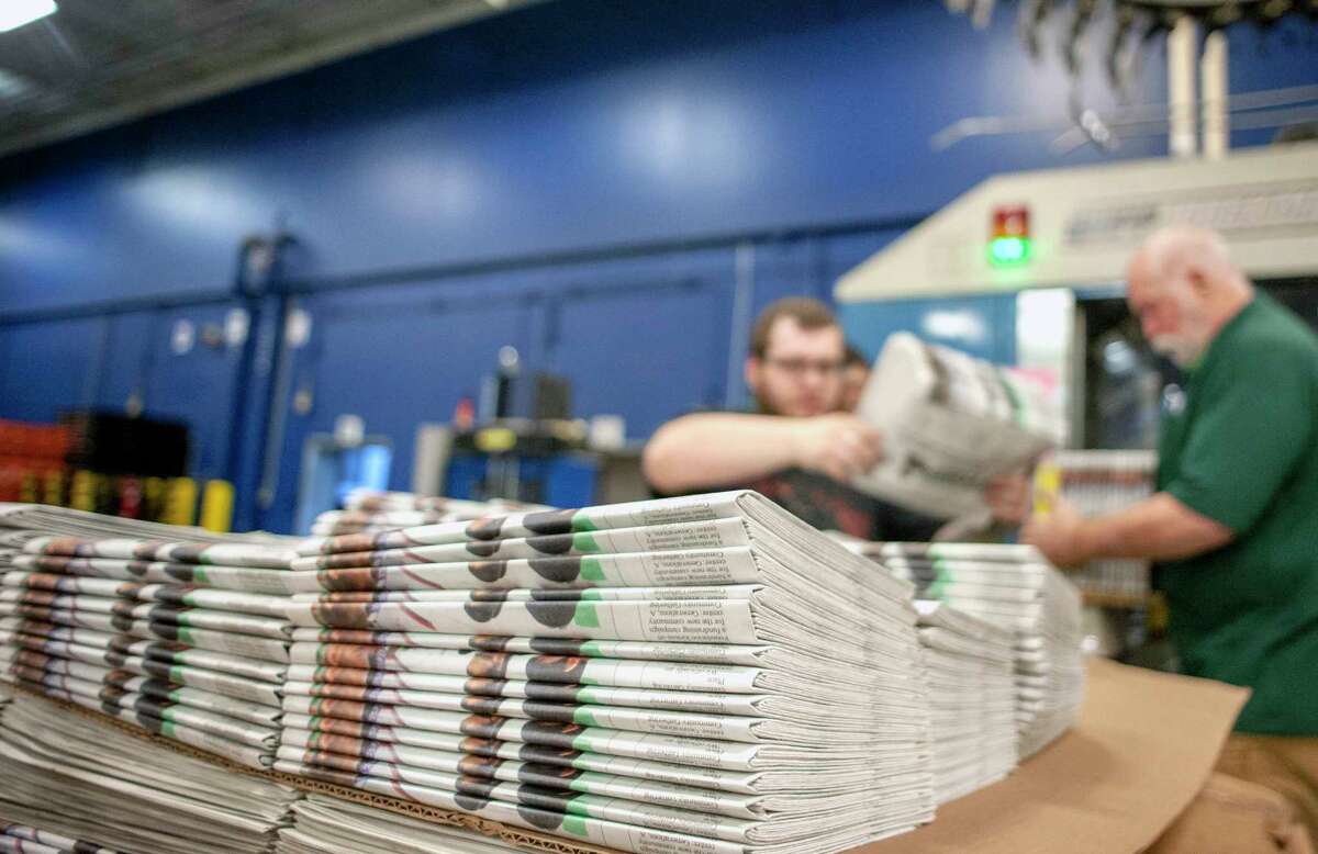 FILE - In this April 11, 2018, file photo, production workers stack newspapers onto a cart at the Janesville Gazette Printing & Distribution plant in Janesville, Wis. The U.S. Commerce Department is going ahead with a tax on Canadian newsprint, a threat to the already-struggling American newspaper industry. The tariffs unveiled Thursday, Aug. 2, are mostly lower than those originally announced earlier this year but would still impose an anti-dumping border tax as high as 16.88 percent. (Angela Major/The Janesville Gazette via AP, File)
