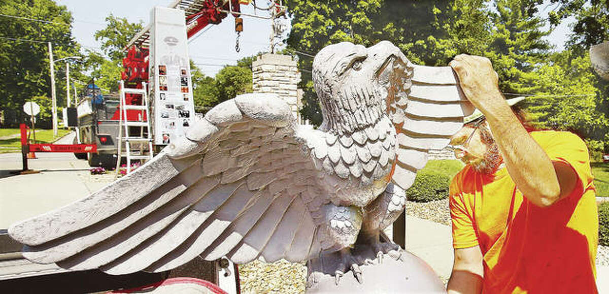 Plasti-Lite Signs employee Bob Stephens prepares the fiberglass eagle, which was fashioned from a mold of a stone eagle on the grounds of the school, for placement back on top of the monument. The previous eagle was badly splintered last year by the impact of the tree.