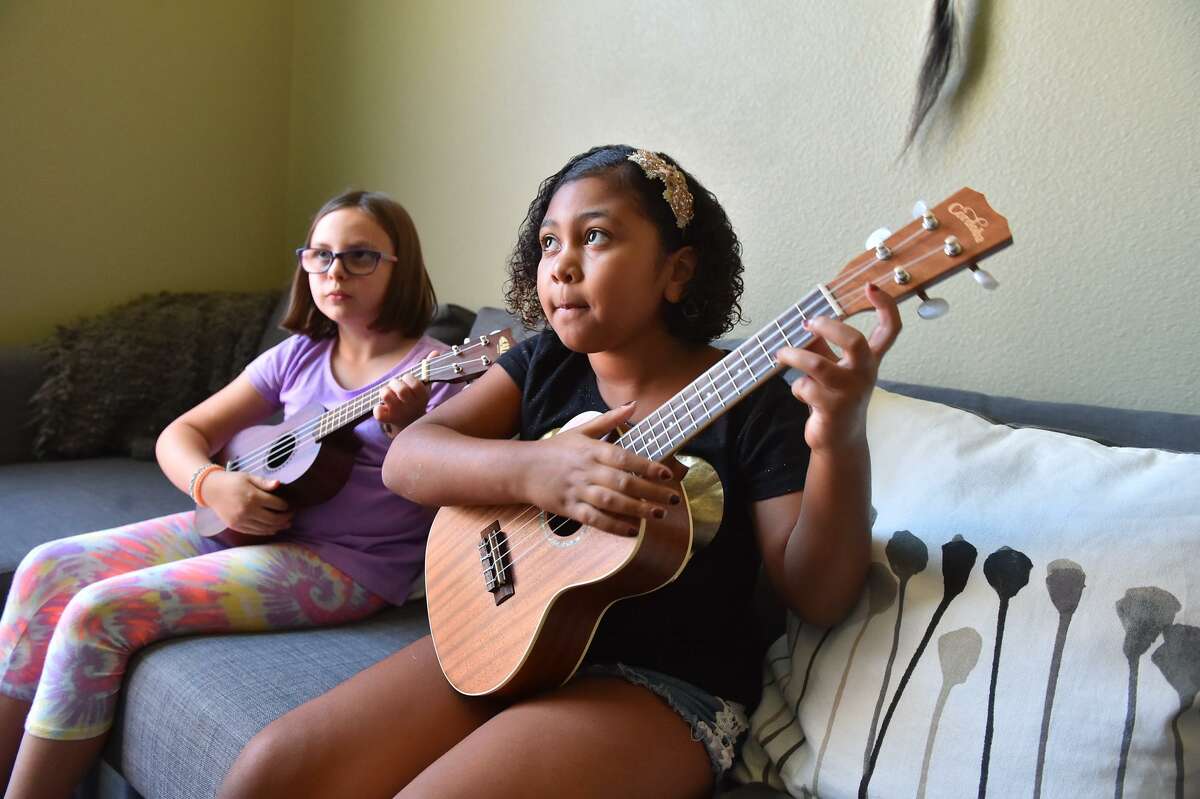 Adalynn Cuevas (right) and Ella Mathias practice the ukulele during their weekly lesson. They are not the lone ukulele rockers of a generation. The instrument’s rising popularity among school kids like Cuevas and Mathias is a part of a wider revival story that has spanned almost four decades.