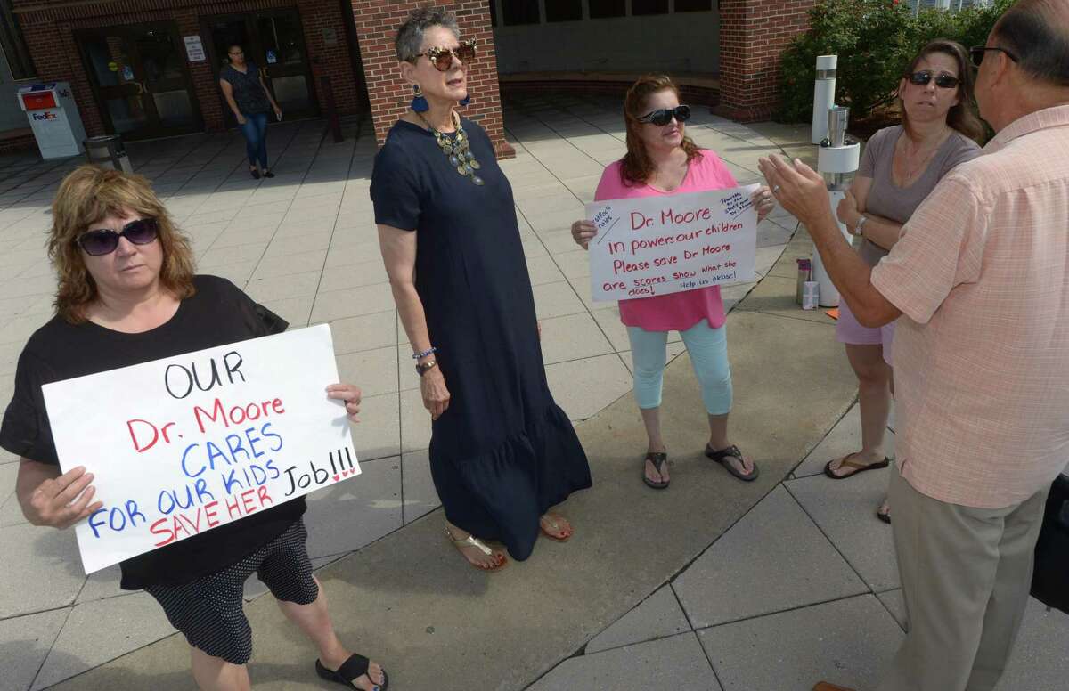 Parents and supporters of West Rocks Middle School principal Lynne Moore, second from left, including Micjhelle DiPalma, Diane Tullio, and Blaire Anderson protest outside City Hall Friday, August 3, 2018, as Moore and Tony Vittrio, right, attend a meeting with Board of Education officials about her imminent dismissal from the school in Norwalk, Conn.