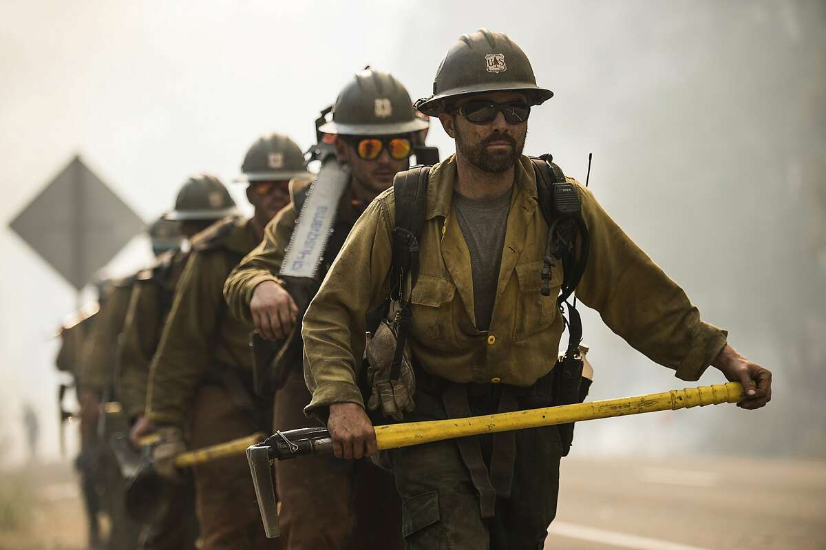 The El Dorado Hotshots battle wildfire near Buckhorn Summit on Highway 299 in Trinity County, Calif., Monday, July 30, 2018. A pair of wildfires that prompted evacuation orders for nearly 20,000 people barreled Monday toward small lake towns in Northern California, and authorities faced questions about how quickly they warned residents about the largest and deadliest blaze burning in the state. (Paul Kitagaki Jr./The Sacramento Bee via AP)
