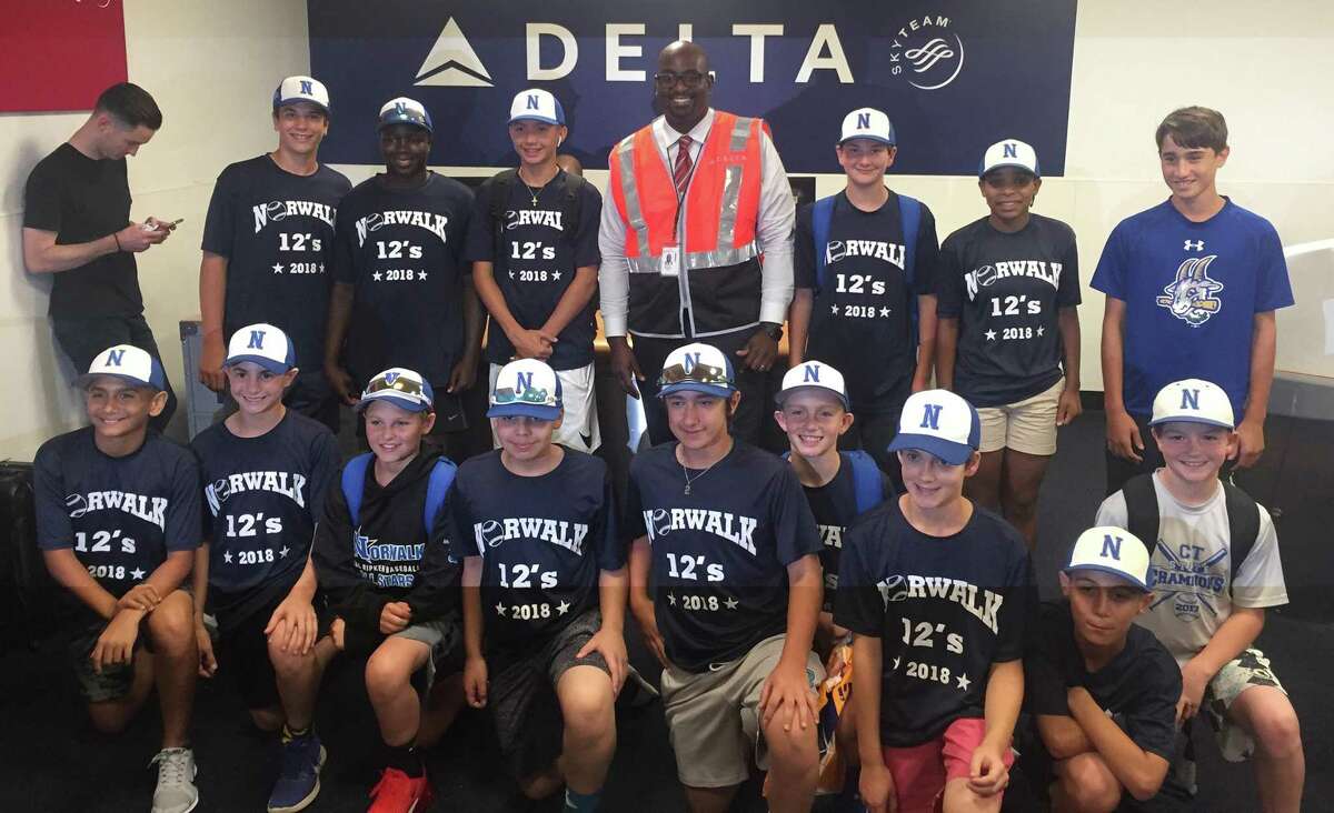 Members of the Norwalk 12-year-old Cal Ripken All-Stars pose for a photo with Delta supervisor Marcus Benjamin near the end of a 10-hour flight delay while en route to Branson, Mo., for the Cal Ripken World Series. Benjamin helped the team charter a flight by finding flight crew members to get the team to Missouri in time for Friday’s opening ceremonies.