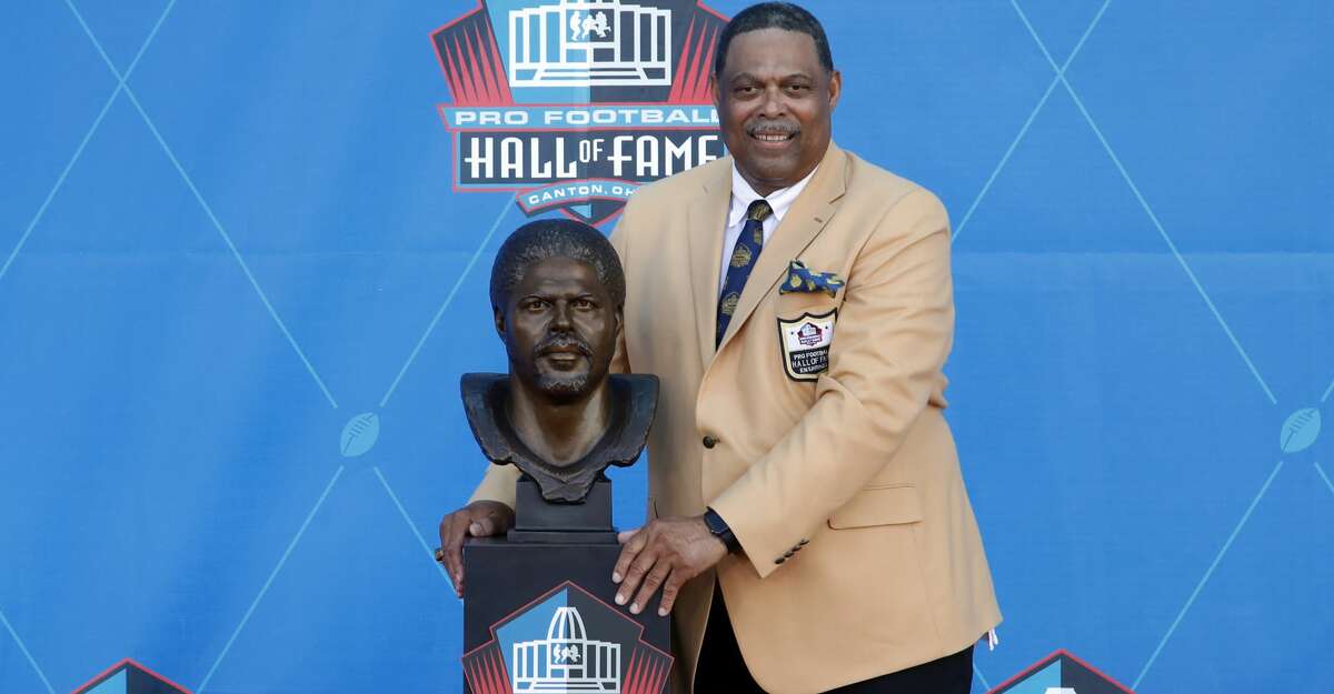 Former NFL player Robert Brazile poses with a bust of himself during inductions at the Pro Football Hall of Fame on Saturday, Aug. 4, 2018, in Canton, Ohio. (AP Photo/Gene J. Puskar)