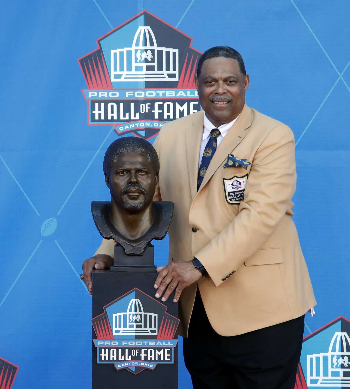 Former NFL player Robert Brazile poses with a bust of himself during an induction ceremony at the Pro Football Hall of Fame Saturday, Aug. 4, 2018, in Canton, Ohio. (AP Photo/Gene J. Puskar)