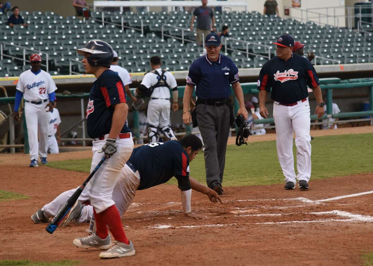 Laredo 18U first baseman Omar Cervantes argues with the umpire showing him his hand marks on home plate after he was ruled out after not touching it.