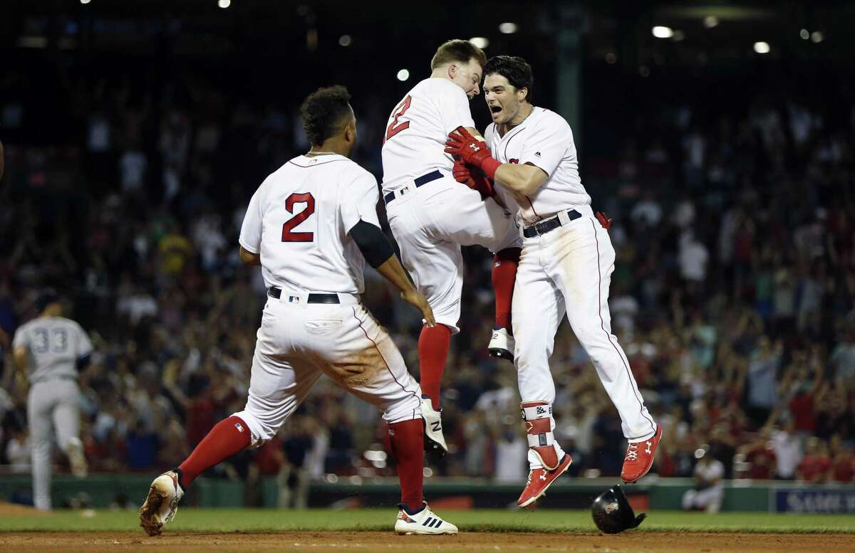 Andrew Benintendi, right, celebrates his game-winning RBI single with Brock Holt, center, and Xander Bogaerts (2) during the 10th inning on Sunday night.