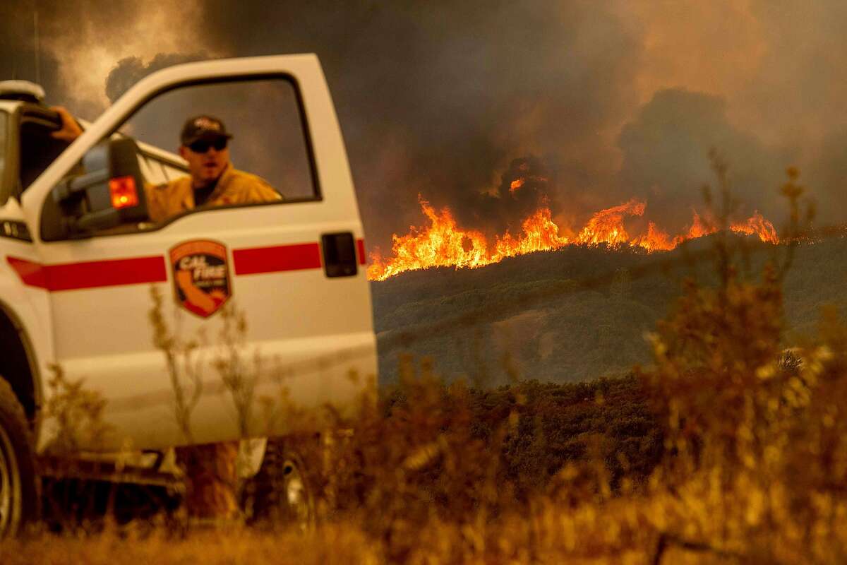 The Ranch Fire, part of the Mendocino Complex Fire, crests a ridge as Battalion Chief Matt Sully directs firefighting operations on High Valley Rd. near Clearlake Oaks, California, on Sunday, Aug. 5, 2018. / AFP PHOTO / NOAH BERGERNOAH BERGER/AFP/Getty Images