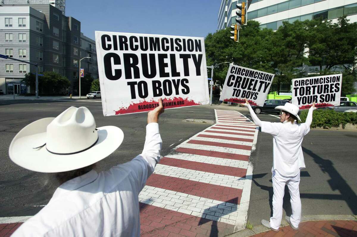 Brett Johnson of Kansas City, right, and a man whose legal name is Brother K or Sacramento hold anti-circumcision signs during a protest at the intersection of Washington Blvd. and Tresser Blvd. in downtown Stamford, Conn. on Tuesday, Aug. 7, 2018. The men are part of the non-profit group Bloodstained Men are currently in the middle of a 21 city tour to help educate people on the reprocussions of male circumcision.