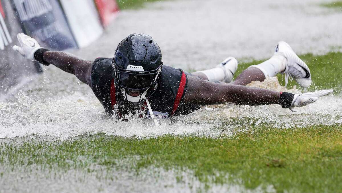 Houston Texans linebackers Whitney Mercilus (59) slides in a puddle of water on the field at the end of practice during training camp at the Greenbrier Sports Performance Center on Friday, Aug. 3, 2018, in White Sulphur Springs, W.Va. A steady rain fell throughout practice.