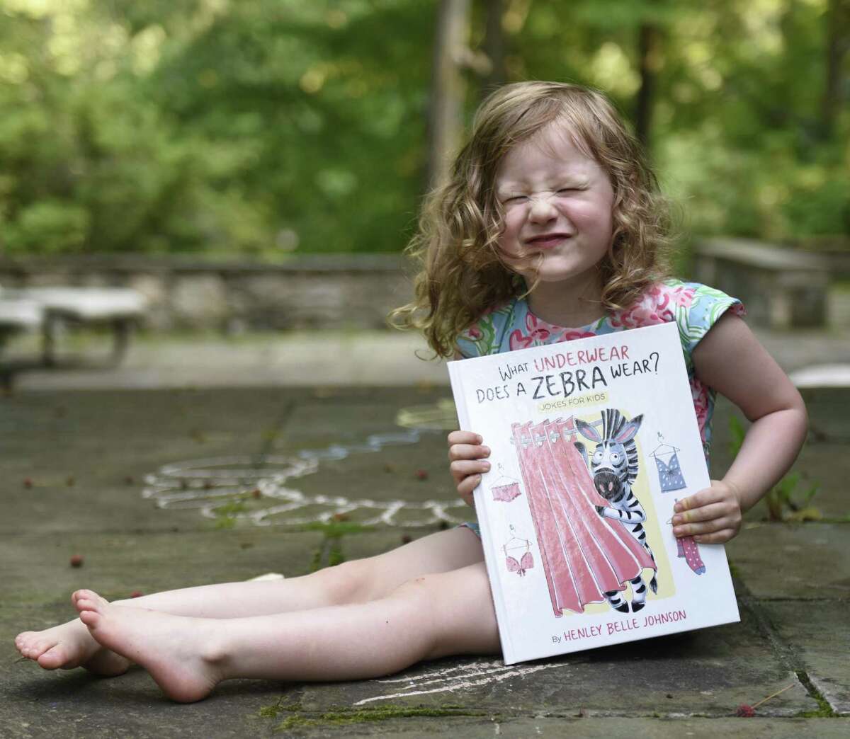 Henley Belle Johnson, 3, shows her new kids joke book “What Underwear Does A Zebra Wear?” at her home in Greenwich on Monday. Elle Muliarchyk and her daughter, Henley, came up with jokes in the new book, which was released in early July and has become an Amazon bestselling children’s joke book.