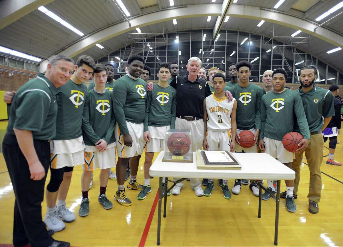 Trinity Catholic High School players and coaches gather around a game ball and City of Stamford Proclamation that was presented at Trinity Catholic High School's Walsh Court in Stamford, Conn. on Jan. 20, 2017 to coach Mike Walsh, center, for his 600th win. Walsh, who is in his 38th season as head coach for the Crusaders, earned his 600th win on Jan 3, 2017 after defeating St. Joseph High School in a FCIAC boys basketball game.