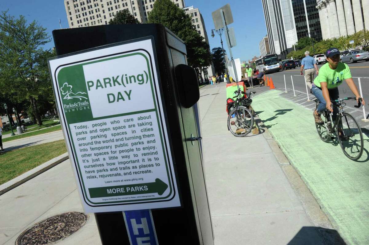 Rossana Coto-Batres, right, with Protected Bicycle Lane Coalition of Albany rides her bicycle in a created bike lane in a parking space on Washington Avenue as part of parking day on Friday Sept. 18, 2015 in Albany, N.Y. (Michael P. Farrell/Times Union)