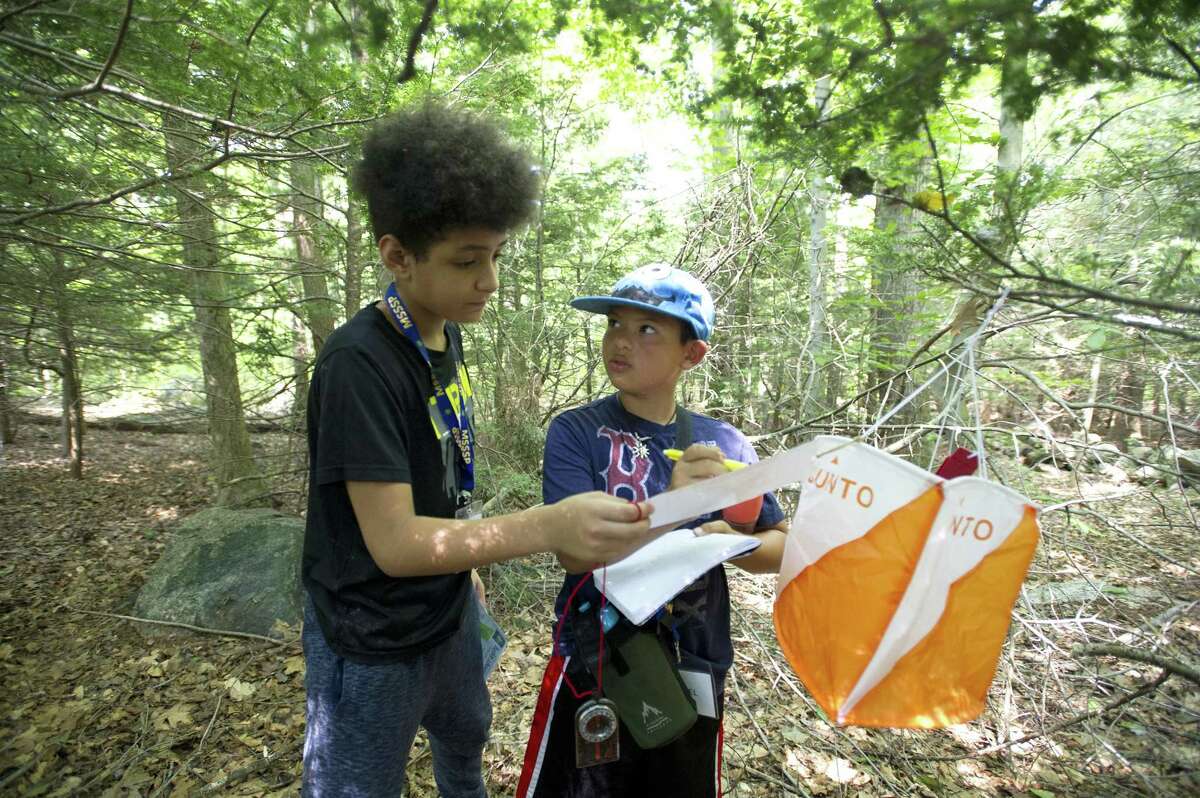 11-year-old Daniel Giron, right, looks at 11-year-old Jonathan Redic while working together to solve a math equation during the Practical Investigations of Science and Math (PRISM) camp at the Bartlett Arboretum in Stamford, Conn. on Tuesday, Aug. 7, 2018. The campers used a compass and various clues to find hidden markers in the woods which contained math problems that needed to be solved.