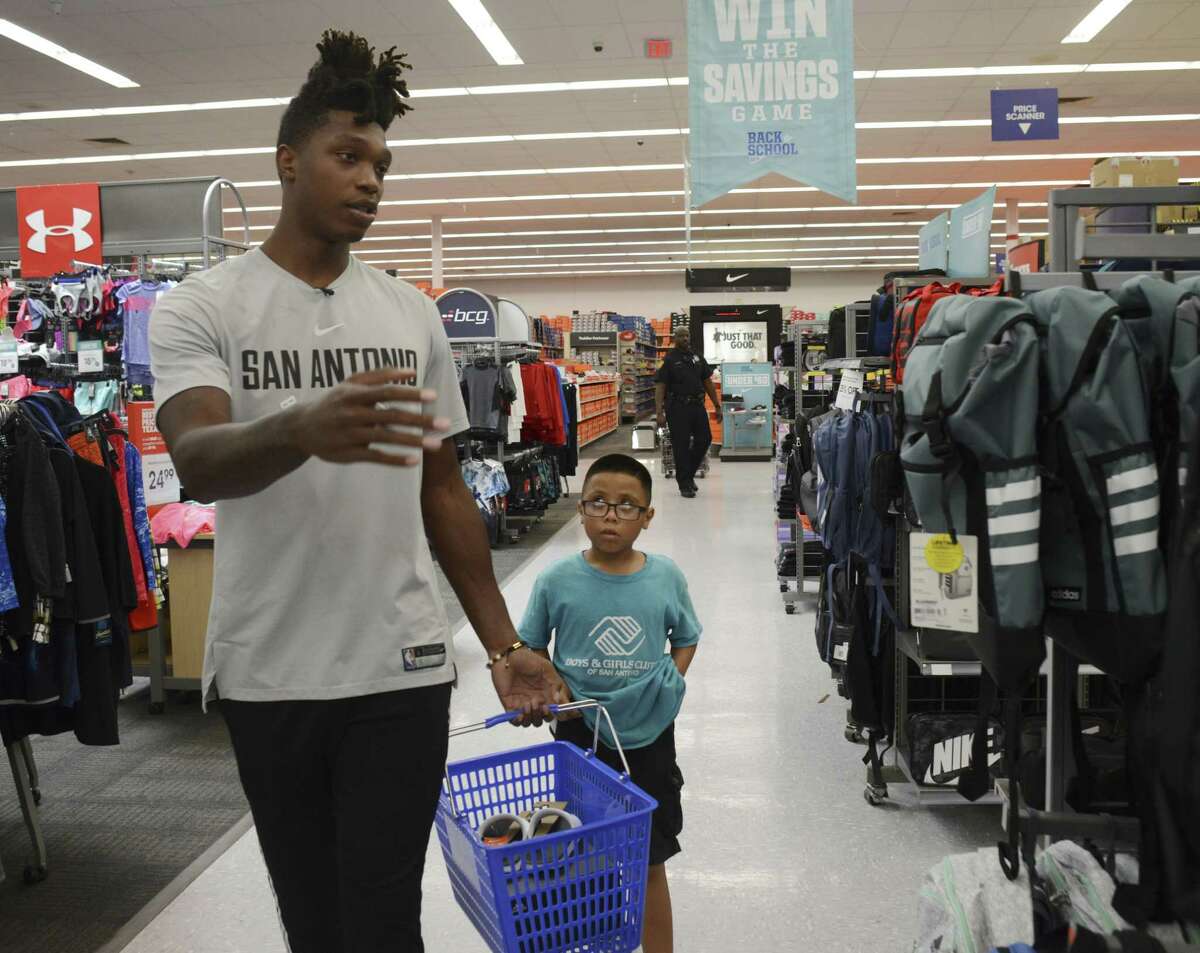 Spurs guard Lonnie Walker IV helps Zach Reyna as he and 60 other children went on a back-to-school shopping spree at Academy Sports + Outdoors on Wednesday.