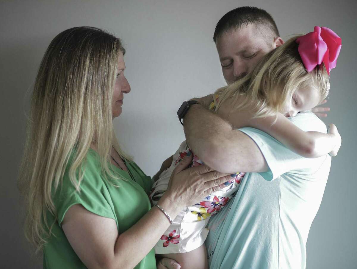 Kevin Leago hugs his daughter, Kenzie, 5 as he wife, Breck, in their Winnie, Texas home on Saturday, July 28, 2018. Kevin is a Houston firefighter with stage 4 neuroendocrine cancer and has been struggling to get worker's compensation.