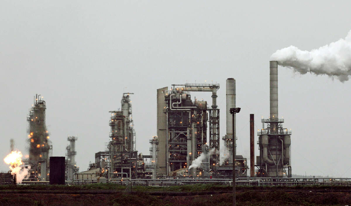This April 2, 2010, file photo, shows a Tesoro Corp. refinery, including a gas flare flame that is part normal plant operations, in Anacortes, Wash. The plant is among those likely to be affected if Washington state becomes the first in the nation to pass a tax on carbon pollution from fossil fuels such as coal, gasoline and natural gas.