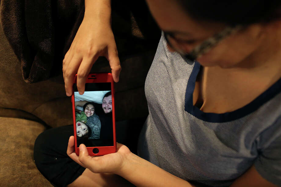 Danielle Kelley shows photos of her with Devin and their son, Michael, 3, at her  Cibolo home on July 10, 2018. (Lisa Krantz | San Antonio Express-News) / San Antonio Express-News
