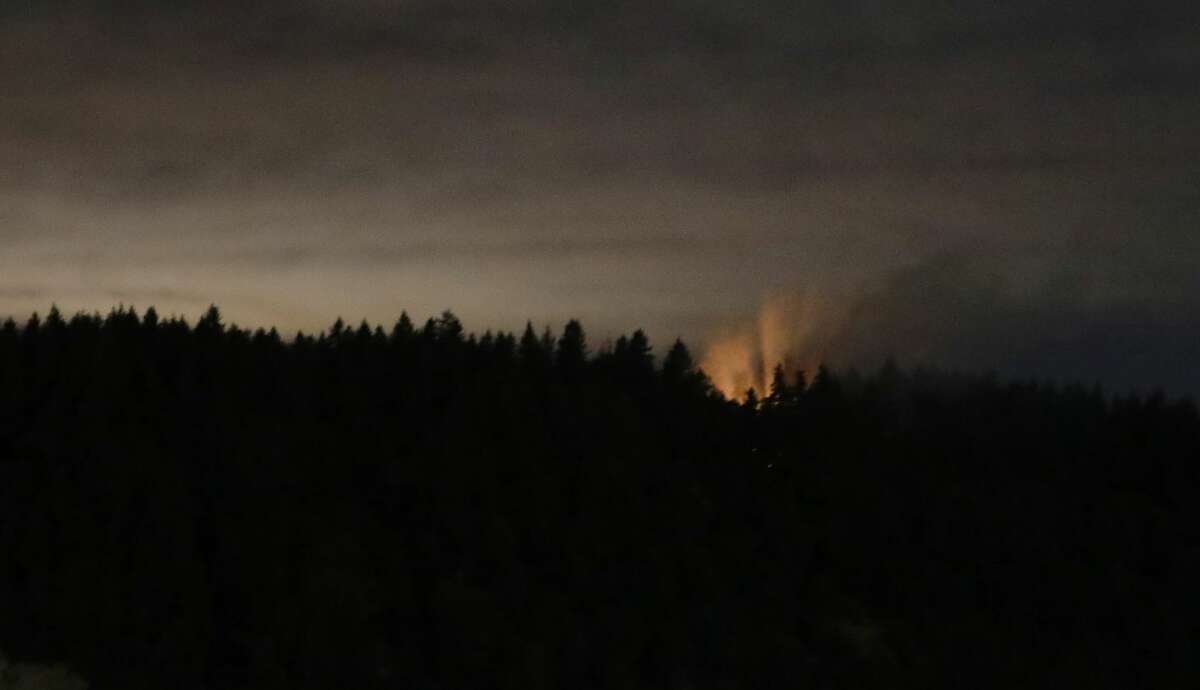 In this long-exposure photo, smoke and an orange glow are seen on Ketron Island in Washington state, early Saturday, Aug. 11, 2018 as viewed from near Steilacoom, Wash. On Friday, an airline mechanic stole an empty Horizon Air turboprop plane, took off from Seattle-Tacoma International Airport and was chased by military jets before crashing onto Ketron, a small island in the Puget Sound, on Friday night, officials said. (AP Photo/Ted S. Warren)