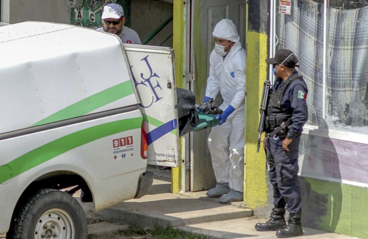 Forensic personnel load onto a van, one of the ten bodies found in a clandestine grave inside an apartment, at Villa Fontana Aqua neigbornhood, in Tlajomulco, Jalisco state, Mexico, on August 8, 2018.