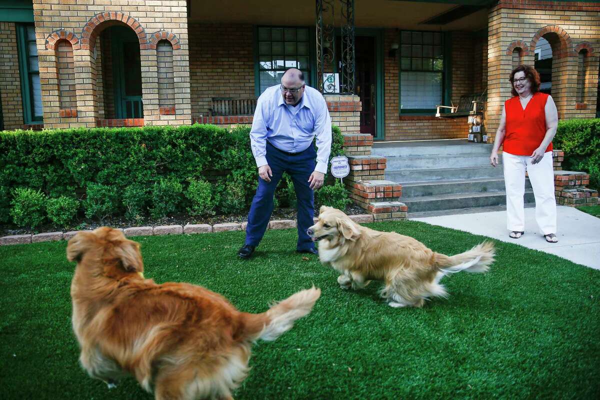 Randall and Etna Neighbour play with their dogs on their new artificial turf lawn Wednesday Aug. 8, 2018 in Houston.