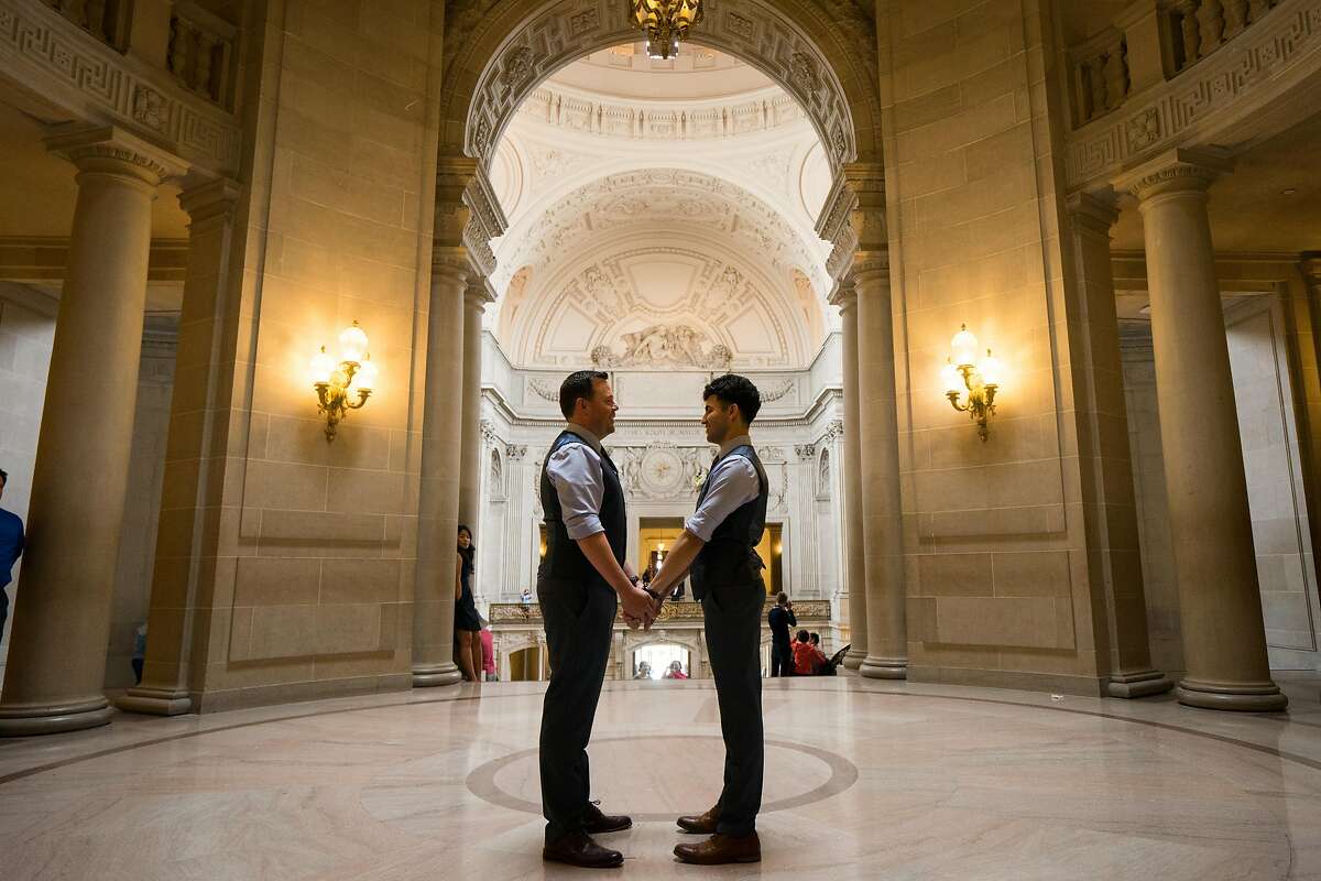 Deric Harris (left) and Michael Alba Huizar hold hands after their wedding ceremony at City Hall in San Francisco, Calif. on Monday, August 13, 2018.
