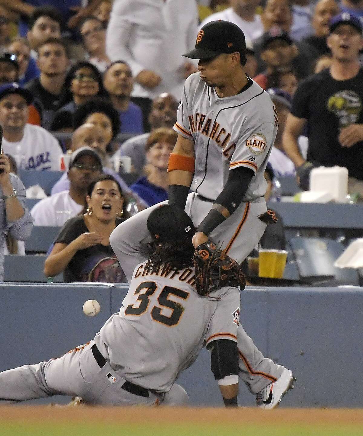 San Francisco Giants left fielder Gorkys Hernandez, top, collides with shortstop Brandon Crawford as they try to field a ball hit for an RBI double by Los Angeles Dodgers' Clayton Kershaw during the fourth inning of a baseball game Monday, Aug. 13, 2018, in Los Angeles. Kershaw was thrown out at third on the play. (AP Photo/Mark J. Terrill)