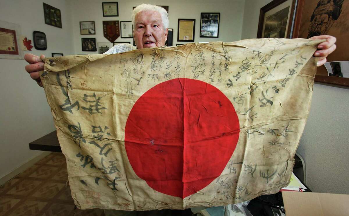Retired Army Capt. Clarence Sprouse holds up a silk Japan flag explaining how the flags are presented to soldiers joining the Japan military forces and signed by family and loved ones. The flag iwas carried, sometimes worn under the uniform. Sprouse collected a number of these, stating, "you might be able to see the bullet hole where he was shot". Sprouse recalls his days fighting in WWII, Korea, Vietnam, and as head trainer for the Cuban Bay of Pigs. He has been called "The Perfect Soldier" by some of his superiors. Friday, Oct. 14, 2011. Photo Bob Owen/rowen@express-news.net
