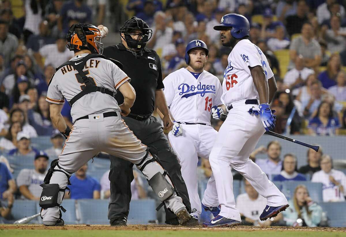 San Francisco Giants catcher Nick Hundley, left, reacts to being shoved by Los Angeles Dodgers' Yasiel Puig, right, as they argue while home plate umpire Eric Cooper, second from left, gets between them and Max Muncy runs in during the seventh inning of a baseball game, Tuesday, Aug. 14, 2018, in Los Angeles. (AP Photo/Mark J. Terrill)