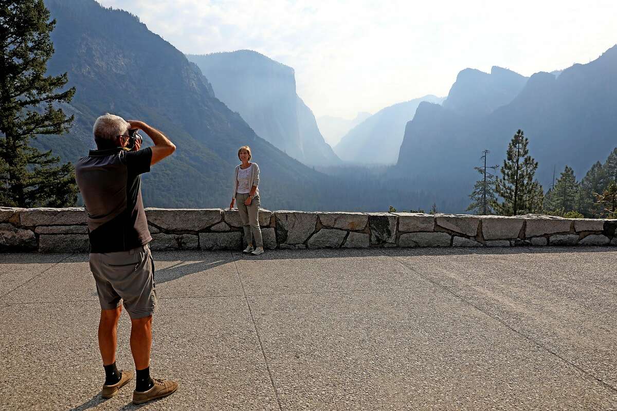 Dario Raffaelli, left, of Piza, Italy, photographs his wife, Paola Raffaelli, at Tunnel View as the Yosemite Valley reopens in Yosemite, Calif., on Tuesday, Aug. 14, 2018, in the wake of the Ferguson fire. (Gary Coronado/Los Angeles Times/TNS)