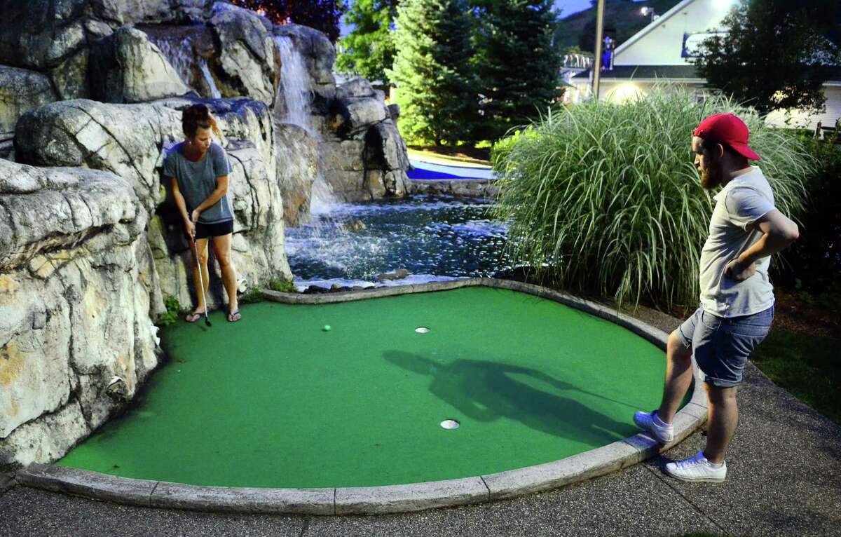 Emil Welles looks on as his wife Julia tries to sink a putt as they play a round of miniature golf at the Sports Center of Connecticut in Shelton.
